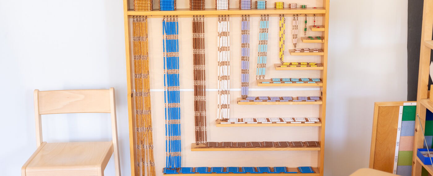 Perlenregal aus Holz mit buntem Perlenmaterial zur Multiplikation.