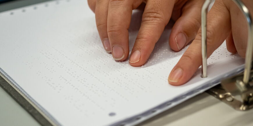 Zwei Hände lesen mit den Fingern Braille.