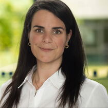 Portraitfoto Ayse Preis - sie trägt das lange dunkle Haar offen und hat ein weiße Bluse an.