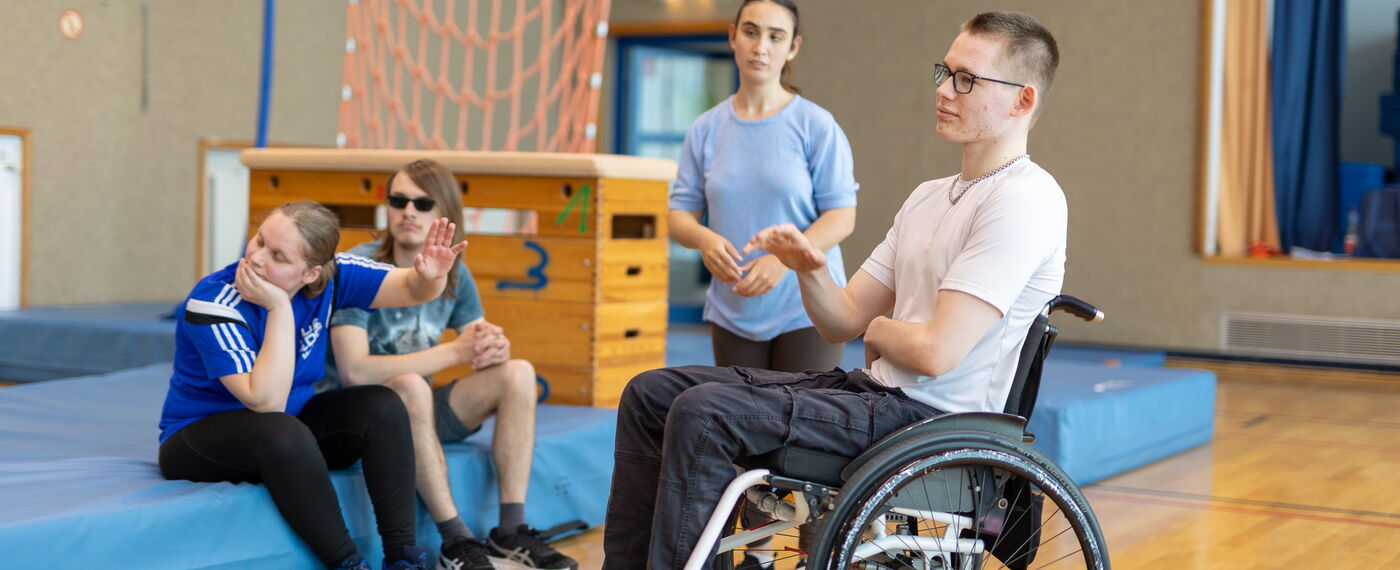 Vier Schüler*innen in der Sporthalle in einem Unterrichtsgespräch.