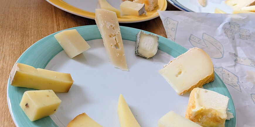 eine Mitarbeiterin von Wein und Käse richtet 10 verschiedene Käsesorten auf einem Teller an-