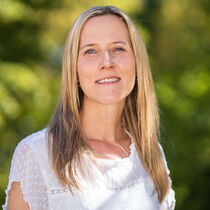 Portraitfoto Sarah Löser - Sie trägt das lange blonde Haar offen und hat eine weiße Bluse an.