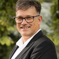 Portraitfoto Otfrid Altfeld - trägt eine Brille und ein weißes Hemd unter einem dunklen Sakko.