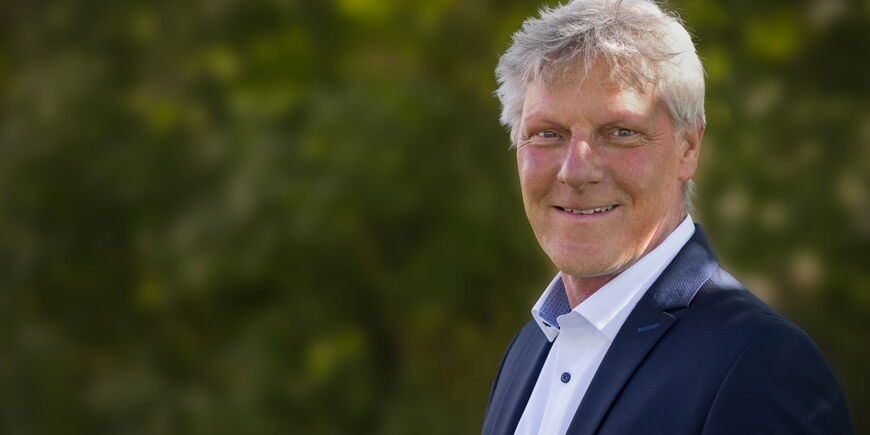 Portraitfoto Maarten Kubeja - er hat kurzes graues Haar und trägt ein blaues Sakko über einem weißen Hemd.