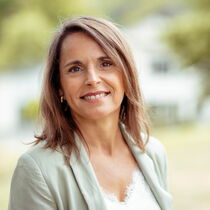 Portraitfoto Monica Wenz-Ramos - sie hat schulterlanges braunes Haar und trägt eine hellgrüne Bluse.