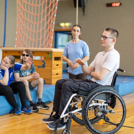 Vier Schüler*innen in der Sporthalle in einem Unterrichtsgespräch.
