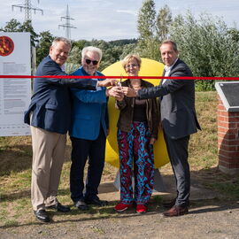 Vor der ca. 1,60m großen gelben Sonne des Planetenwegs stehen Thomas Spies, Hans Junker, Cornelia  Dörr und Patrick Temmesfeld und durchschneiden ein rotes Band.