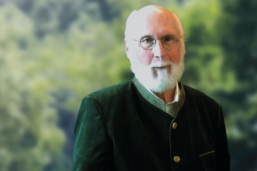 Portrait Jochen Fischer, er trägt einen Trachtenjanker, eine runde Brille und hat einen weißen Vollbart.