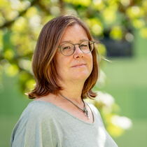Portraitfoto Tanja Schapat - Sie trägt das rötliche Haar offen und ein türkises T-Shirt.