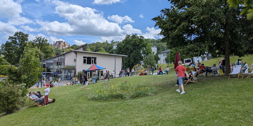 Viele Menschen bevölkern den sommerlichen blistaCampus mit Liegestühlen und Zelten.