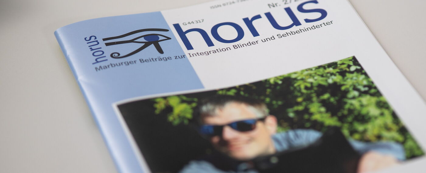 Eine Ausgabe der Zeitschrift horus liegt auf einem weißen Tisch.