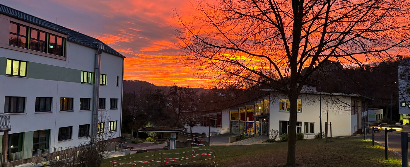 Der blistaCampus in der Dämmerung vor einem rot leuchtenden Abendhimmel