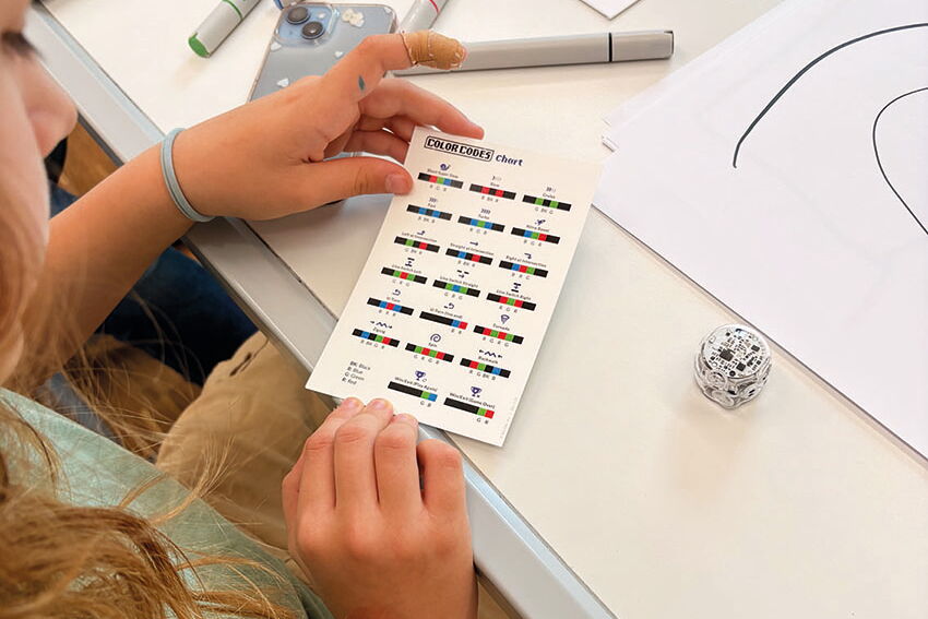 Eine Schülerin hält einer Karte in der Hand, mit der man die Ozobots programmieren kann.