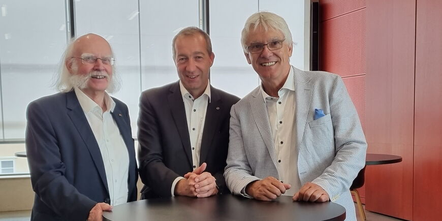 Jürgen Hertlein, Patrick Temmesfeld und Claus Duncker stehen festlich gekleidet an einem Stehtisch.