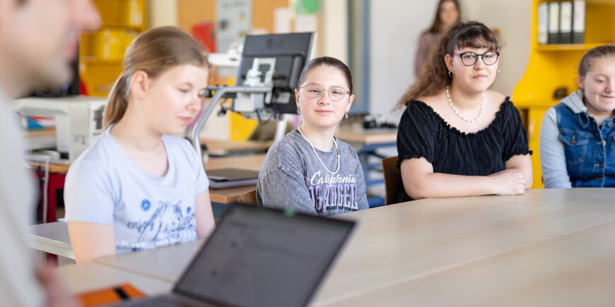 Vier Schüler*innen sitzen an einem Tisch.