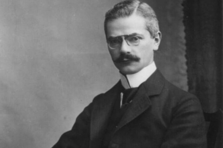 Historisches Schwarzweiß-Foto eines Herren mit kurzem Haar, Brille, Schnauzbart und Anzug.