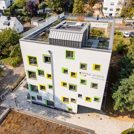 Das Schulgebäude der Montessorischule mit seinen grün umrandeten, verspielt angeordneten Fenstern aus der Luft