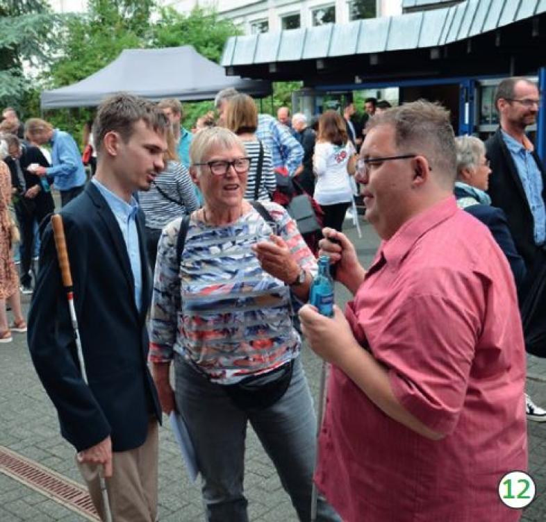 Vor der blista Turnhalle stehen nach der Feier viele Menschen ins Gespräch vertieft.