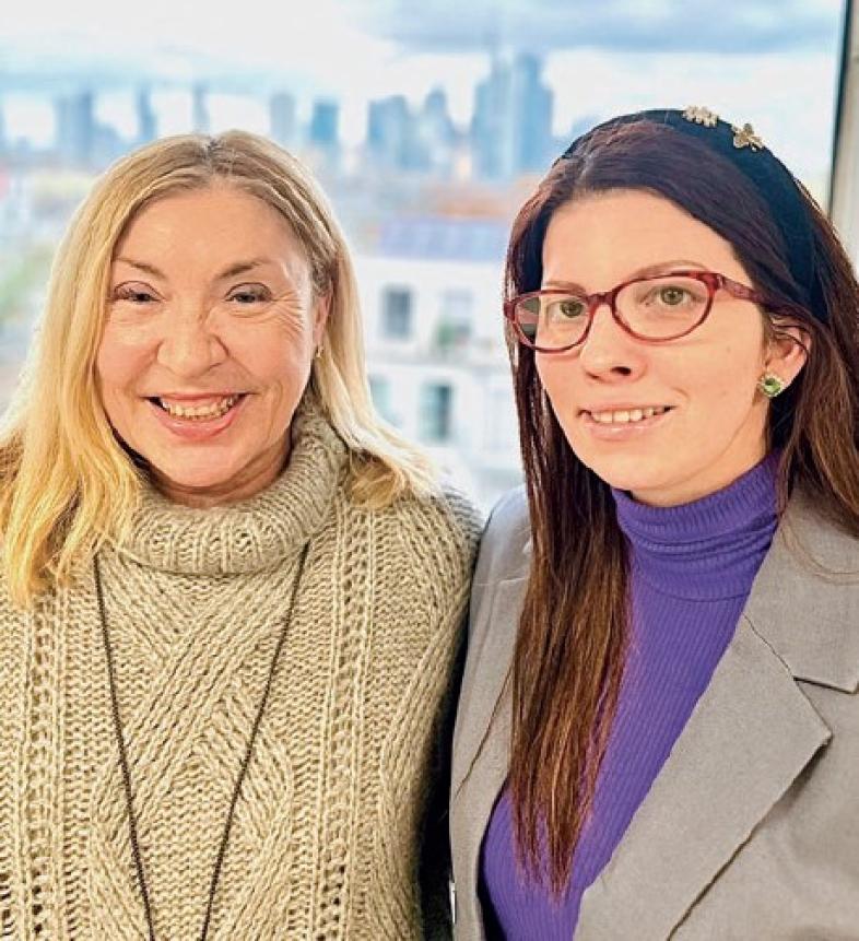 Auf dem Bild sind Martina Borghardt und Kristina T. vor der Frankfurter Skyline zu sehen, die fröhlich in die Kamera lächeln. 