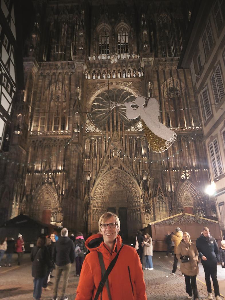 Alexander Tyssen steht winterlich gekleidet vor dem weihnachtlich beleuchteten Münster in Straßburg.