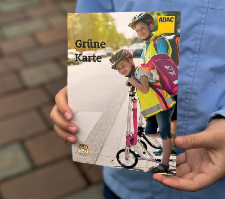 Zwei Hände halten die „grüne Karte“ des ADAC für vorbildliches Verhalten im Straßenverkehr