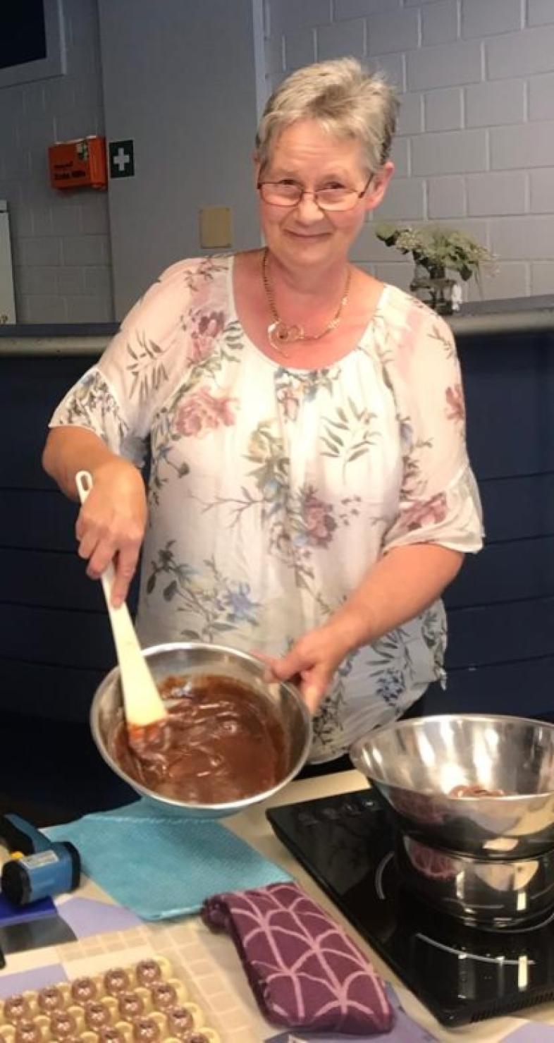 Uta Willms zeigt gutgelaunt ihre kulinarischen Künste und rührt in einer Edelstahlschüssel Schokolade.