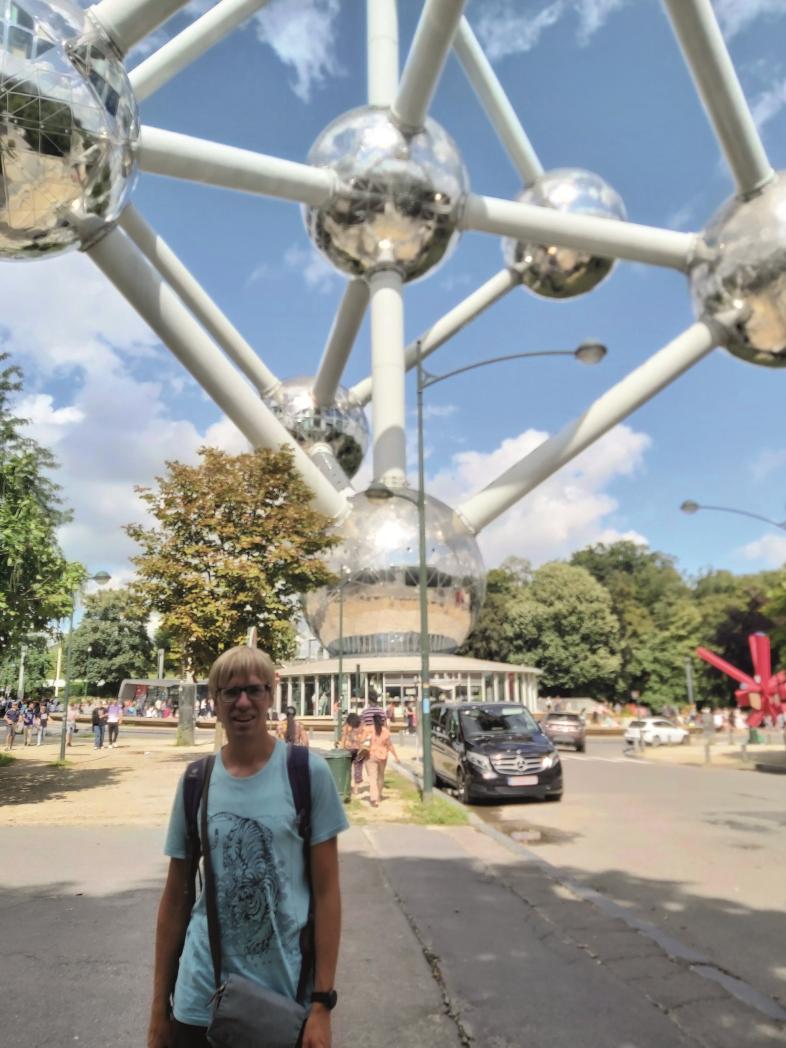 Alexander Tyssen steht in sommerlicher Kleidung vor dem Atomium in Brüssel