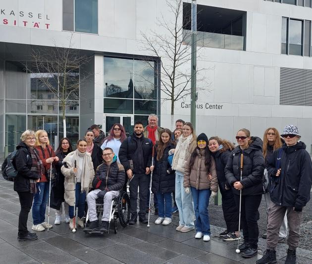 Die Schüler*innen der Fachoberschulen stehen gemeinsam mit ihren Lehrkräften vor einem Gebäude der Universität Kassel.